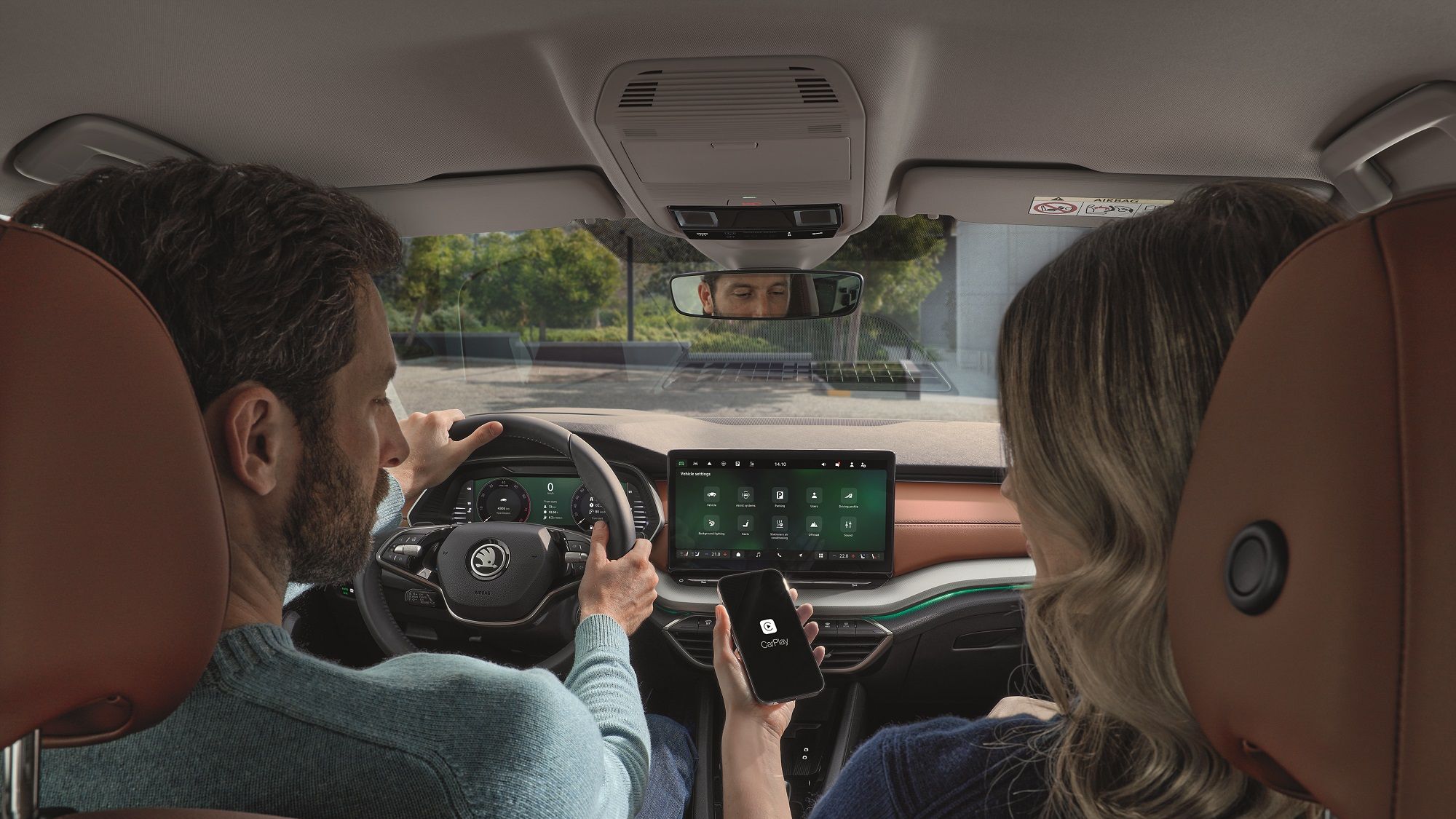 A man driving the Skoda Octavia, a women in the passenger seat connecting her phone to apple car play