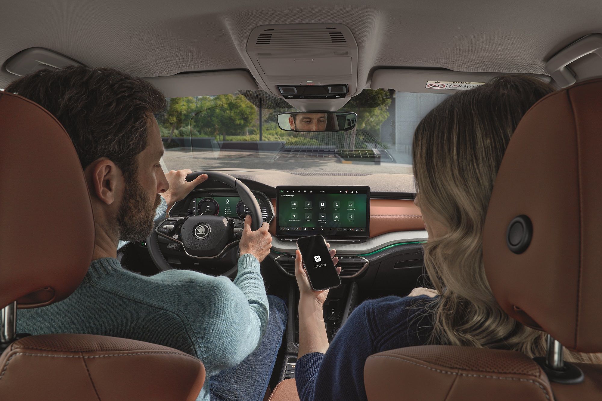 A man driving the Skoda Octavia, a women in the passenger seat connecting her phone to apple car play