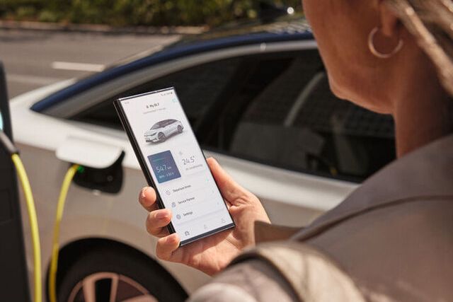 A lady holding her phone showing her MySkoda app